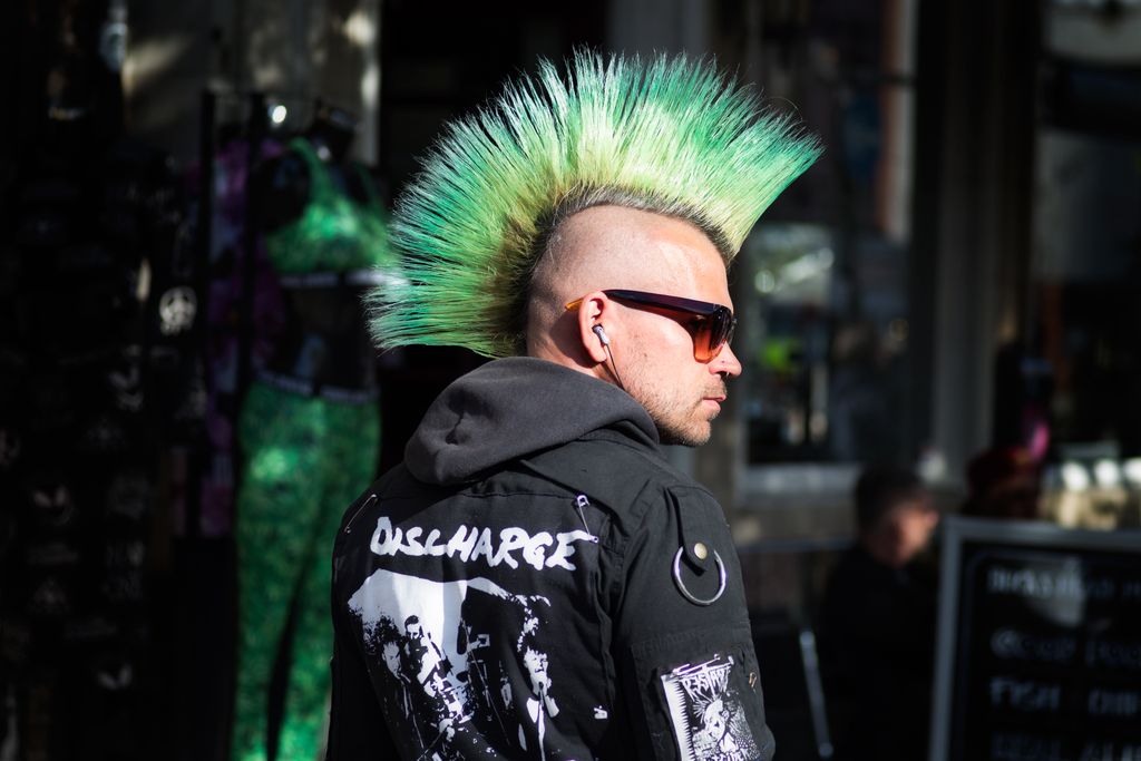 Portrait of a punk fashion enthusiast in England with a striking green mohawk and sunglasses.
